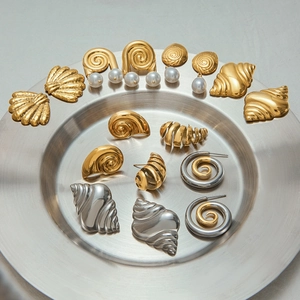 Detailed arrangement of gold and silver shell-shaped pearl earrings on a metal tray
