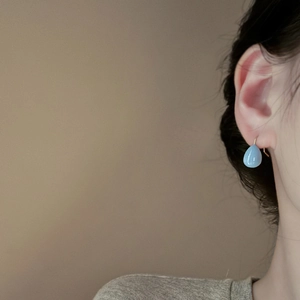 Close-up of a model wearing light blue teardrop tassel earrings with silver hooks
