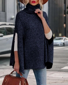 Dettaglio della maglia del maglione poncho a collo alto blu scuro sulla modella