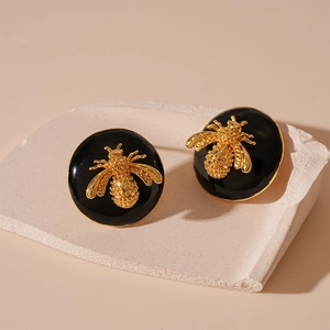 Detail view of vintage bee earrings featuring black enamel and gold metallic textures