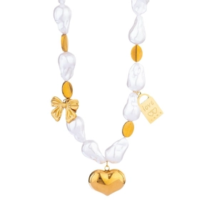 Collier en perles baroques avec pendentif coeur doré et nœuds sur un fond blanc pur