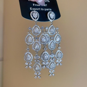 Macro detail of silver-tone tassel earrings with teardrop zircon crystals and floral design