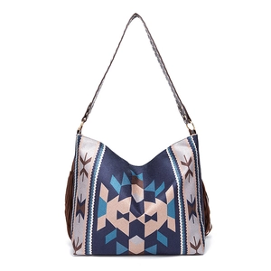 Detail of bohemian woven shoulder bag featuring navy ethnic patterns and side tassels