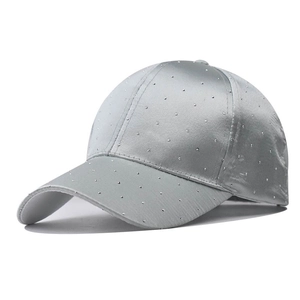 Detail of silver satin baseball cap featuring dense rhinestone accents and curved brim
