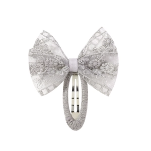 Détail de la pince à cheveux nœud en dentelle grise avec broderie florale et clip BB