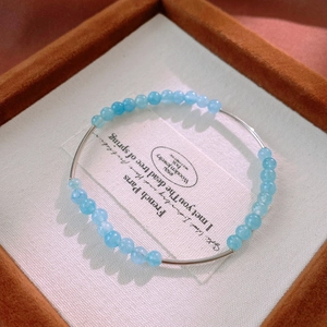 Detail shot of light blue aquamarine beads and silver tubes in a jewelry display box