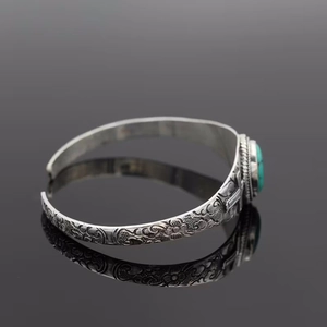 Vintage bohemian silver cuff bracelet featuring embossed flowers and green turquoise stone