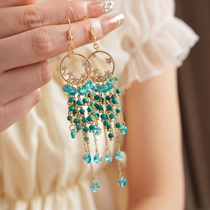 Gros plan de boucles d'oreilles créoles dorées vintage avec pompons en cristal bleu