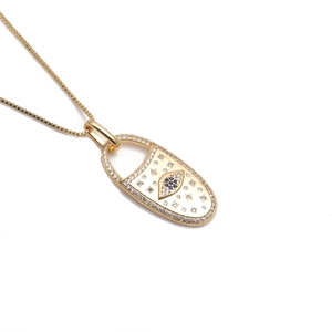 Gold evil eye lock necklace with blue and clear zircon crystals on white background