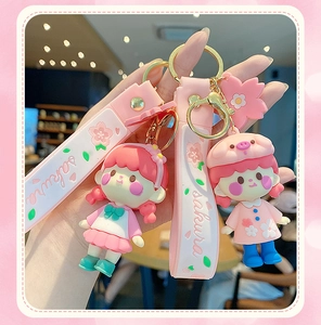 Close-up of cute Sakura girl keychain with pink wrist strap and gold metal clasp