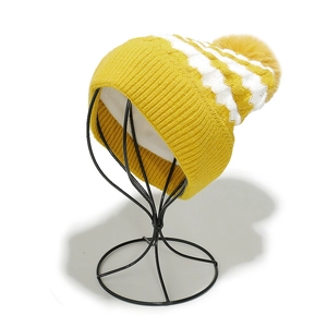 Detailed macro view of yellow and white striped knit beanie with fluffy pom pom on top