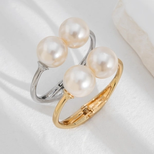 Close-up of elegant gold and silver open bracelets with large polished white pearls