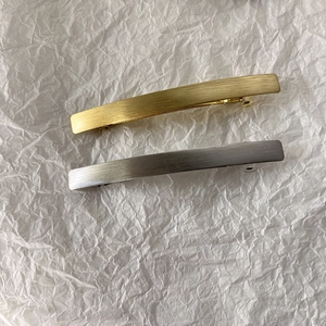 Close-up of gold and silver spring hair clips with a brushed metal texture and curved design