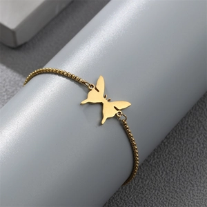 Close-up of golden butterfly pendant on beaded chain bracelet with brushed metal texture
