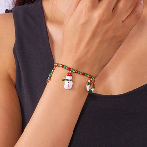 Close-up of Christmas beaded bracelet featuring snowman and tree enamel charms on wrist