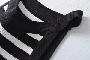 Dettaglio dello scollo in maglia con strisce orizzontali bianche e nere su tessuto a coste