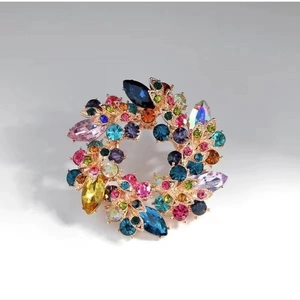 Macro shot of circular crystal wreath brooch with multicolored rhinestones and gold alloy