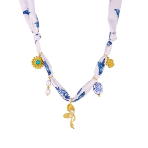 Detail of silk ribbon necklace with blue butterfly print, pearls, and gold pendants