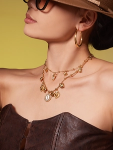 Close-up of layered owl pendant necklace and large hoop earrings on a model