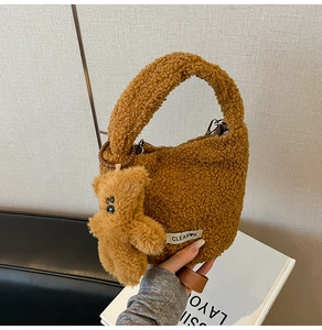 Detail of soft brown faux shearling bucket bag with a cute bear charm and woven strap