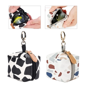 Detail view of mini PU leather pacifier pouch with cow print and terrazzo pattern textures