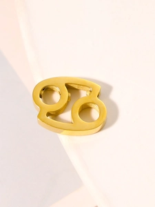 Macro shot of gold Cancer zodiac sign pendant in stainless steel on white steps