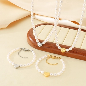 Elegant pearl jewelry set with heart pendants on silk fabric and wooden display stand