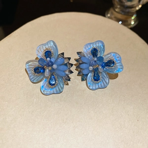 Macro shot of blue crystal flower earrings with teardrop gems and pearl details
