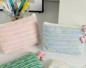 Detail of colorful woven coin pouches with cute pearl and bow zipper charms on desktop