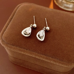 Macro view of teardrop silver zircon earrings resting on a brown velvet jewelry box