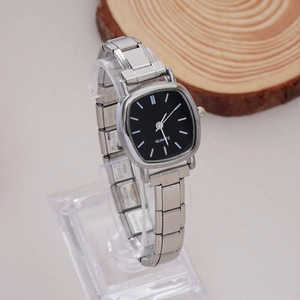 Detail of silver quartz watch with black square dial on rustic wood and light surface
