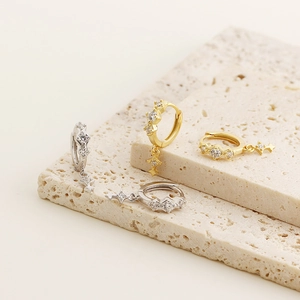 Dettaglio di orecchini S925 in oro e argento con pendenti a stella su base in pietra