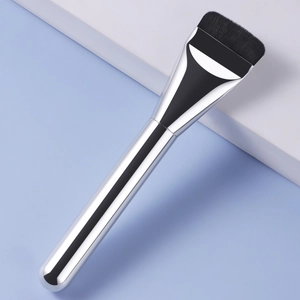 Flat foundation brush with silver metal handle and dark bristles on a blue background