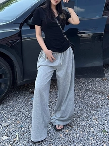 Detail of slim fit black V-neck t-shirt and grey wide-leg joggers in an outdoor setting
