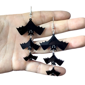 Detail view of black acrylic multi-layer bat earrings with silver hooks for Halloween