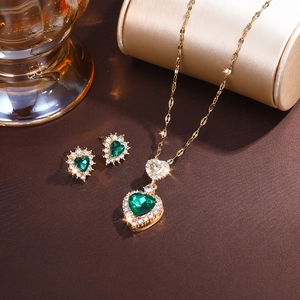 Elegant gold jewelry set with green heart-shaped gemstones and sparkling crystals