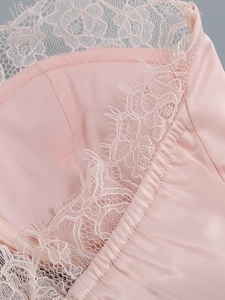 Detail of pink satin dress featuring delicate eyelash lace trim and refined stitching
