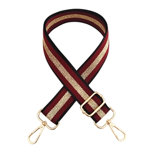 Detail of red and gold striped fabric strap with polished gold metal buckles and texture