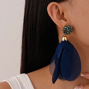 Close-up of deep blue tulle petal fringe earrings with rhinestone studs on model