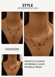 Detail of red strawberry and cherry pendant necklace showing layered gold chain on model