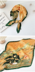 Detail of pleated silk scarf featuring orange floral patterns and green borders