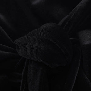 Dettaglio macro del tessuto in velluto nero con pieghe morbide e finitura lucida