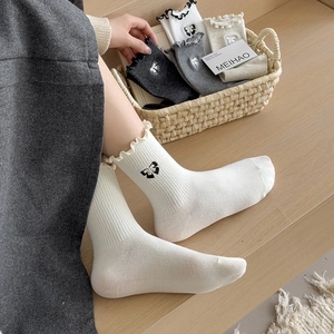 White crew socks with ruffled cuffs and black bow embroidery for a cozy chic look