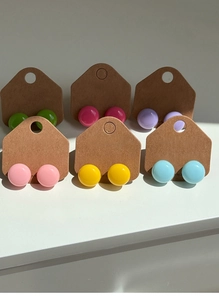 Gros plan de six paires de boucles d'oreilles rondes aux couleurs acidulées sur cartes