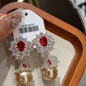 Detail of elegant earrings with red teardrop stone and large champagne pearl charm