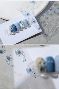 Blue and white porcelain floral nail stickers applied on manicured nails detail view