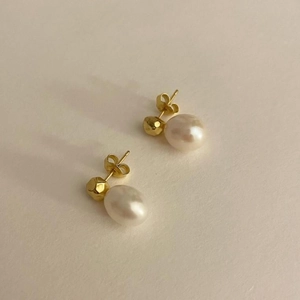 Elegant 925 sterling silver gold pearl earrings with white oval pearls on a beige surface
