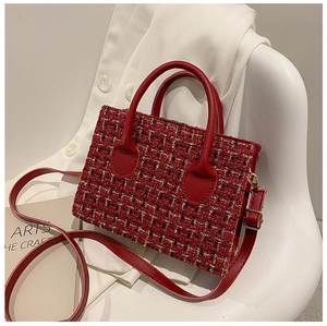 Detail of red tweed small tote bag with leather handle and shoulder strap on a chair