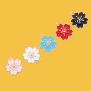 Macro view of five colorful enamel cherry blossom charms for DIY jewelry making and crafts