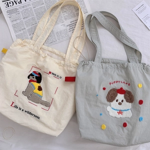 Detailed embroidery of dog pattern and Puppyland text on soft canvas drawstring tote bags